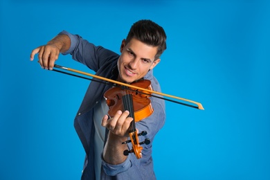 Photo of Happy man playing violin on light blue background