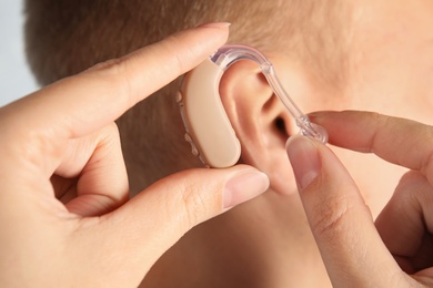 Doctor putting hearing aid in patient's ear, closeup