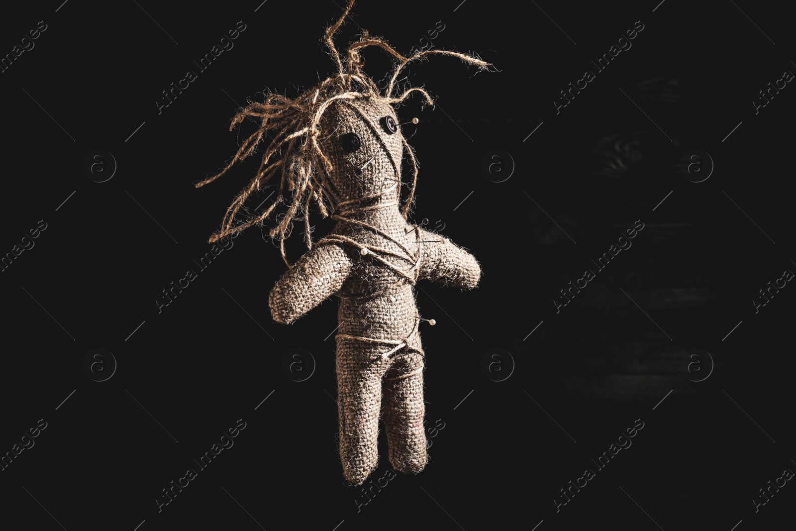 Image of Female voodoo doll with pins on dark background