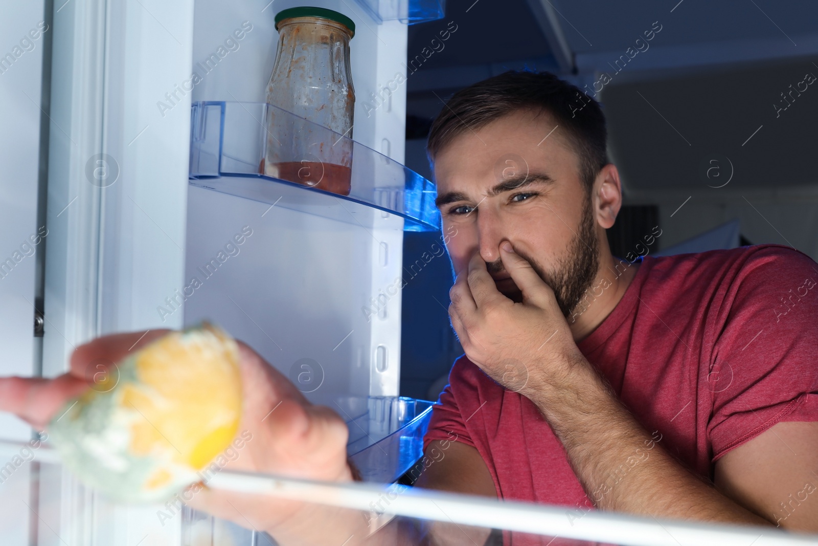 Photo of Man smelling stinky stale cheese in refrigerator