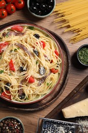 Plate of delicious pasta with anchovies and ingredients on wooden table, flat lay