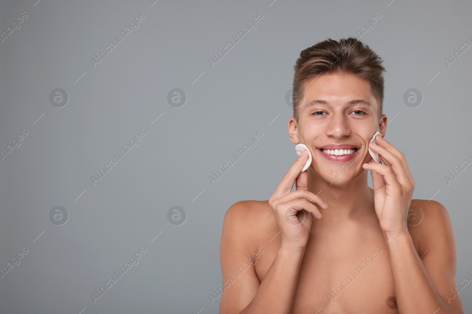 Photo of Handsome man with cotton pads on grey background, space for text