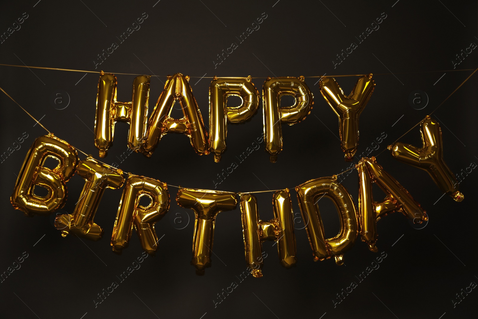 Photo of Phrase HAPPY BIRTHDAY made of golden balloon letters on dark background