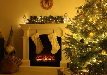 Photo of Stylish fireplace near decorated Christmas tree and accessories in cosy room