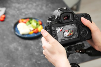 Photo of Woman taking picture of mozzarella salad on table in professional photo studio, closeup. Food photography