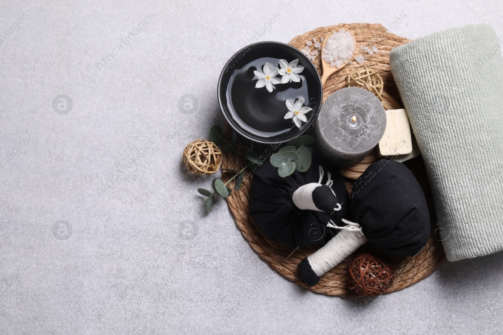 Photo of Flat lay composition with herbal massage bags, spa products and flowers on light grey table. Space for text