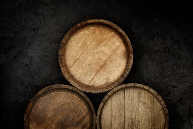 Image of Three wooden barrels near dark textured wall