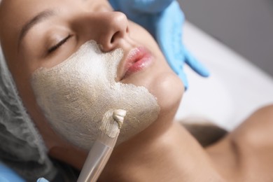 Cosmetologist applying mask on client's face in spa salon, closeup