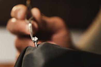Photo of Professional jeweler evaluating beautiful ring, closeup view
