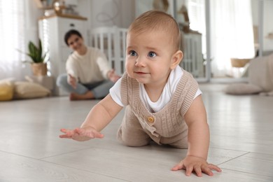Photo of Happy mother watching her cute baby crawl on floor at home