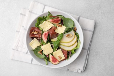 Tasty salad with brie cheese, prosciutto, pear and figs on light grey table, top view