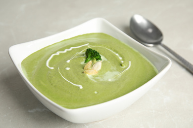 Photo of Delicious broccoli cream soup served on grey marble table