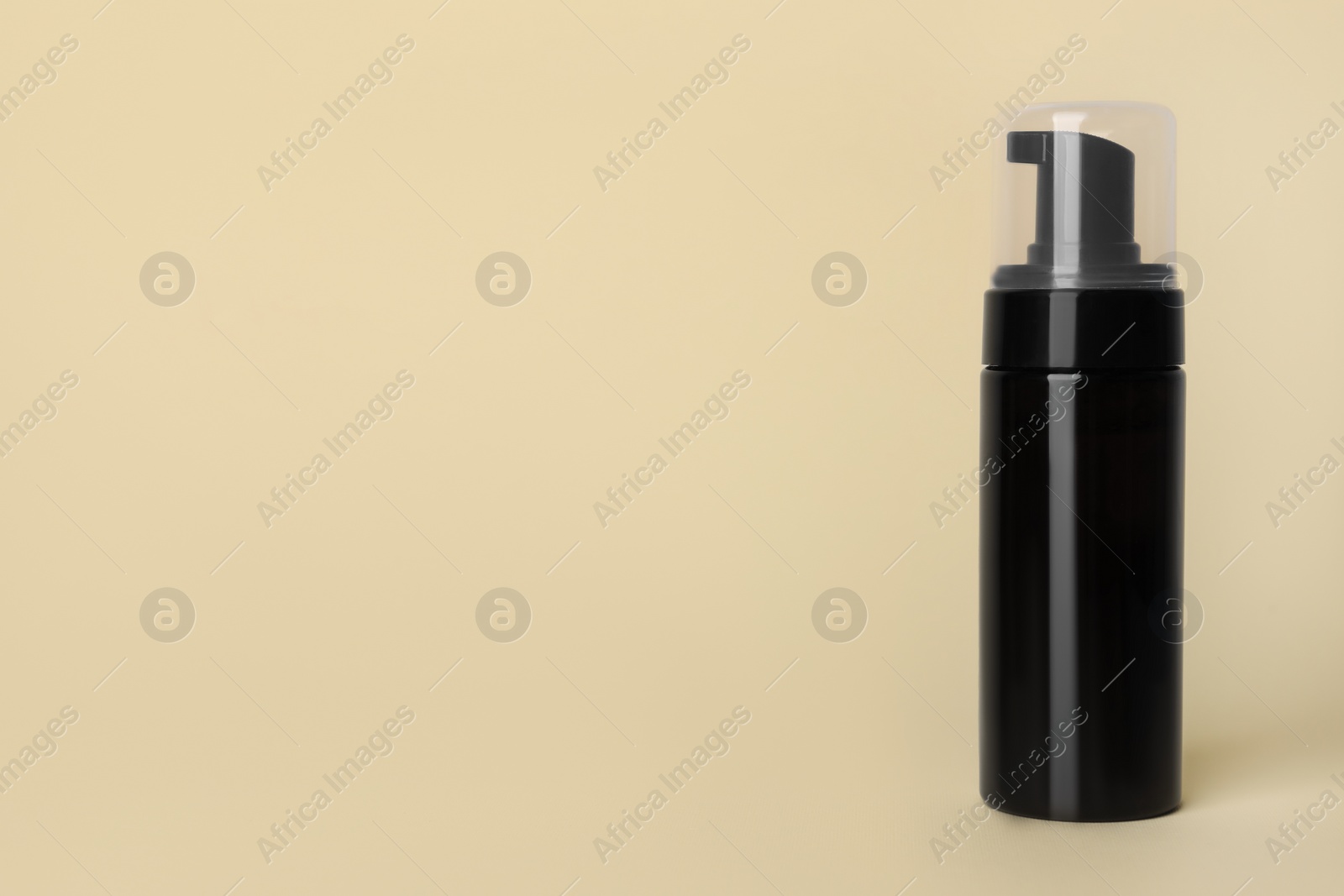 Photo of Bottle of face cleansing product on beige background. Space for text