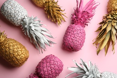 Photo of Different painted pineapples on pink background, above view. Creative concept
