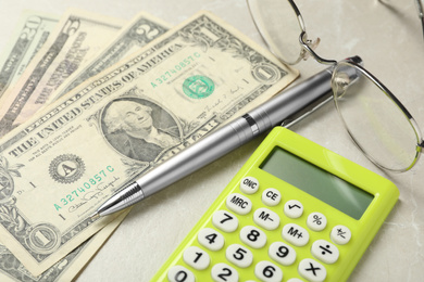 Photo of Calculator, pen, money and glasses on light table, closeup. Tax accounting