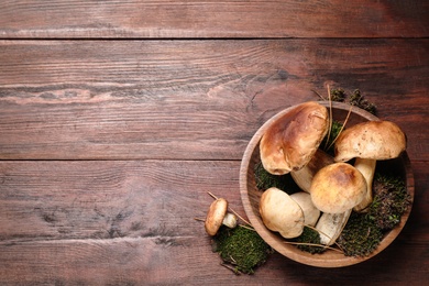 Photo of Fresh wild porcini mushrooms on wooden table, top view. Space for text