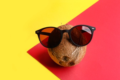 Funny face made of coconut and sunglasses on color background. Vacation time