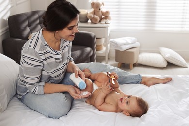 Mother with dusting powder near her cute baby at home