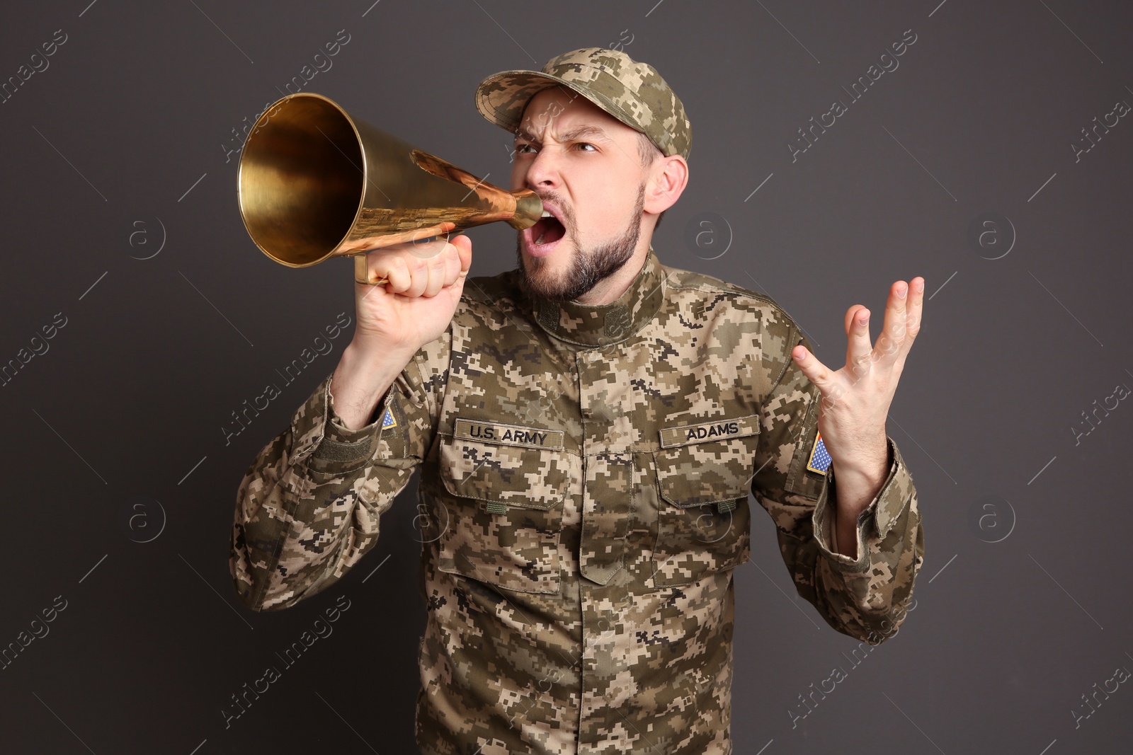 Photo of Military man shouting into megaphone on gray background