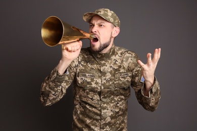 Photo of Military man shouting into megaphone on gray background