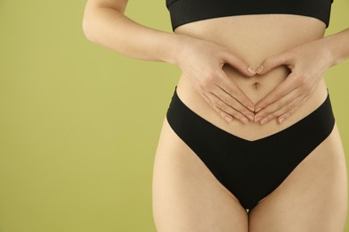 Photo of Gynecology. Woman in underwear making heart with her hands on green background, closeup. Space for text