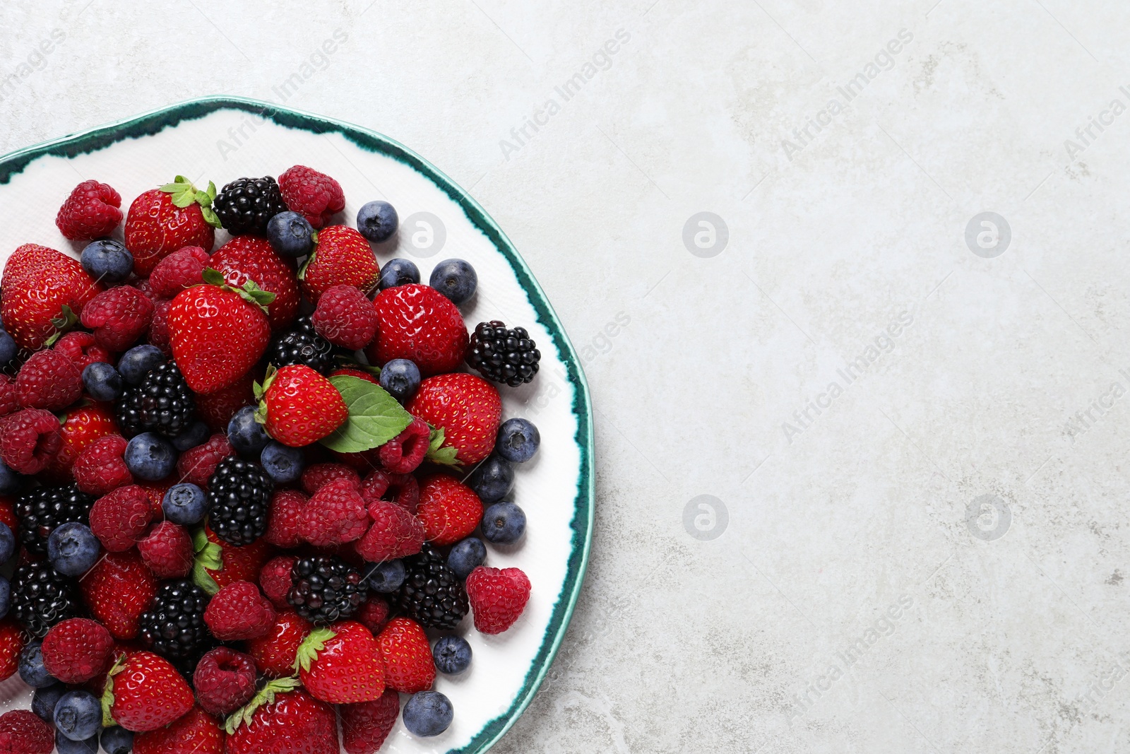 Photo of Different fresh ripe berries on light grey table, top view. Space for text