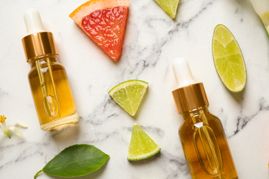 Flat lay composition with bottles of citrus essential oil on white marble background
