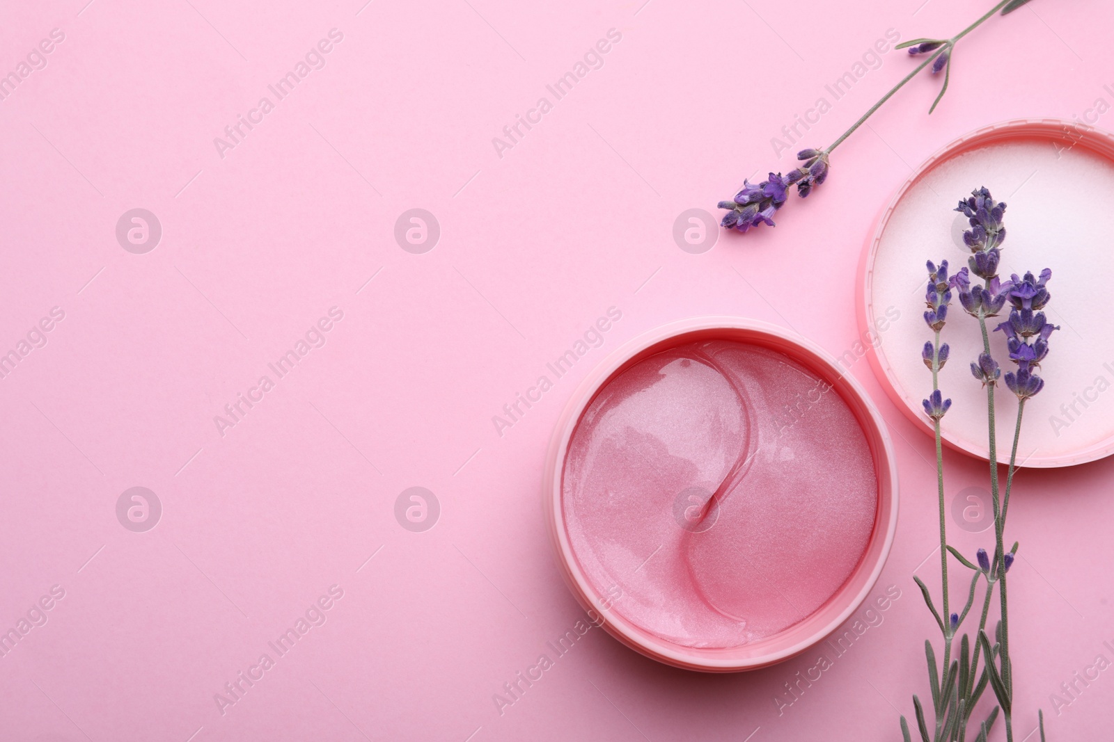 Photo of Package of under eye patches and lavender flowers on pink background, flat lay with space for text. Cosmetic product