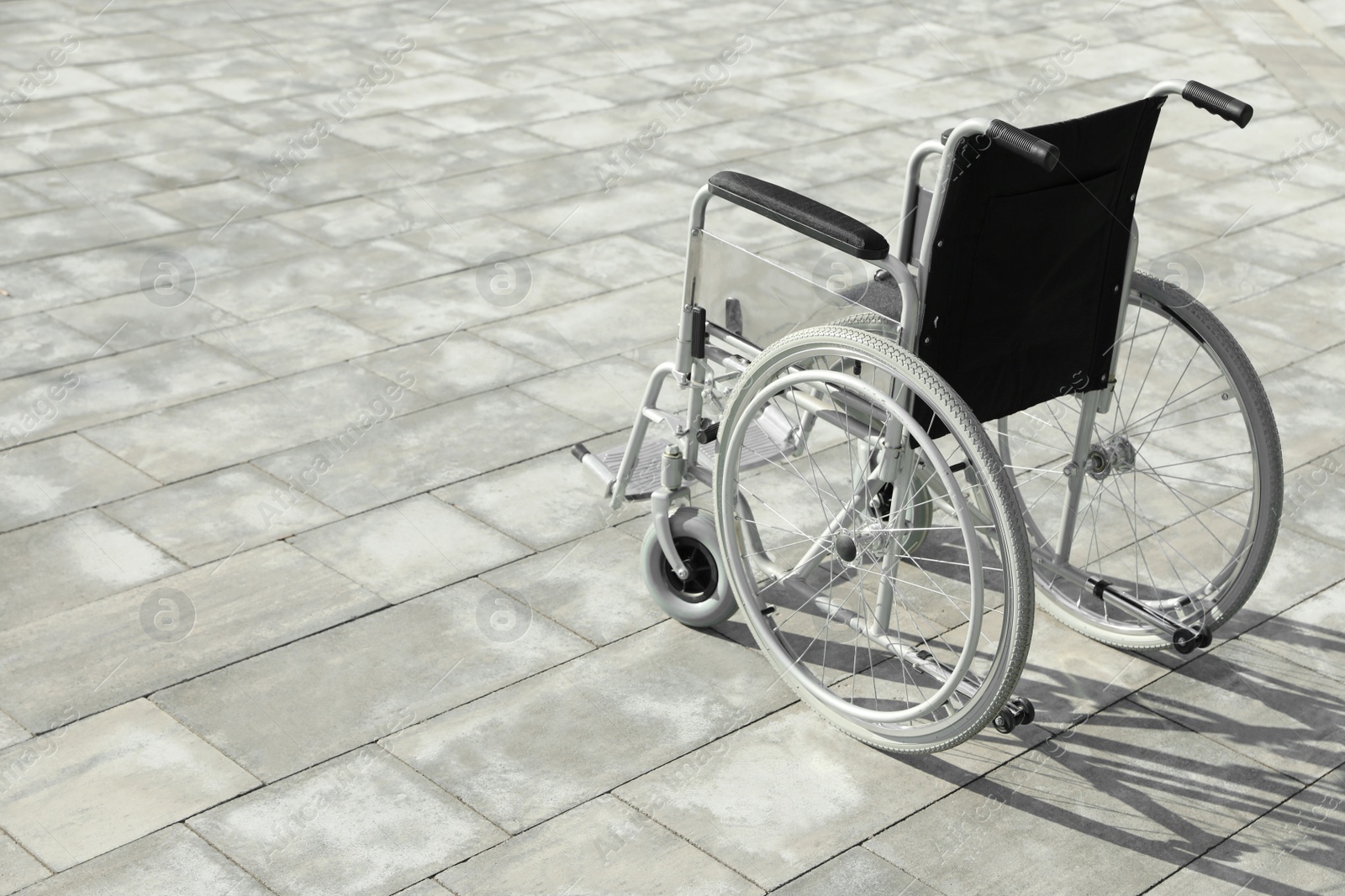 Photo of Empty wheelchair outdoors on sunny day. Space for text