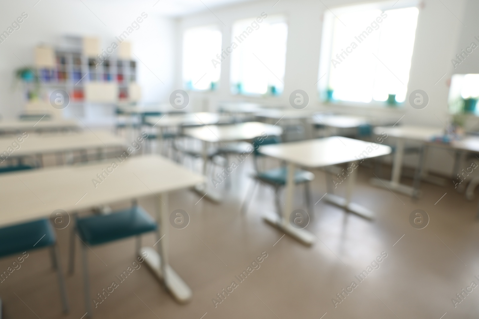 Photo of Blurred view of empty school classroom with desks, windows and chairs