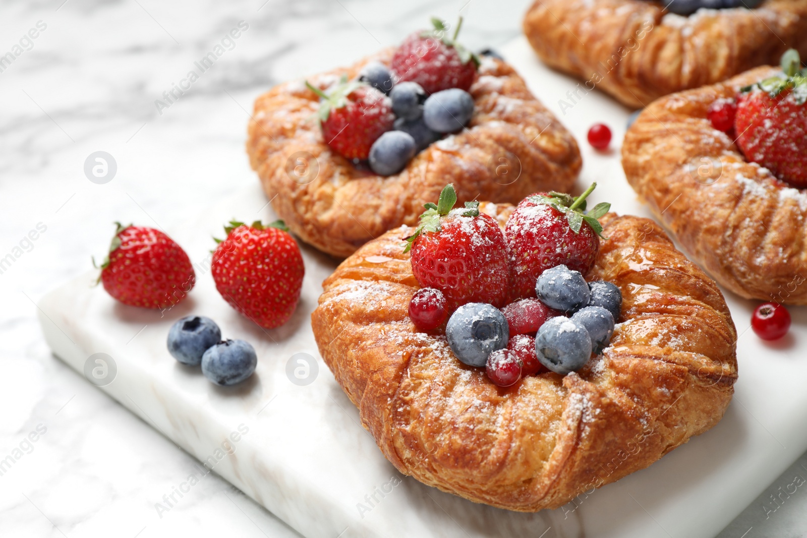 Photo of Fresh delicious puff pastry with sweet berries on white marble board, closeup