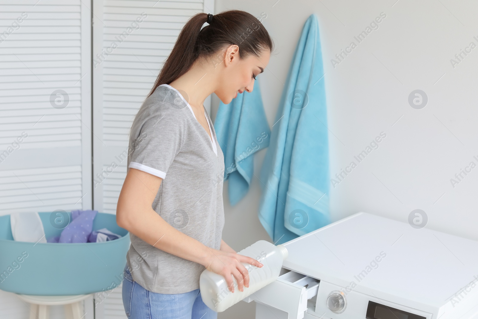 Photo of Young woman doing laundry at home