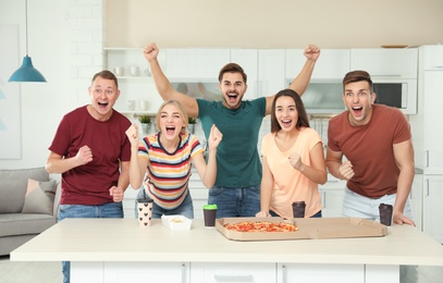 Photo of Group of friends with tasty food laughing together in kitchen