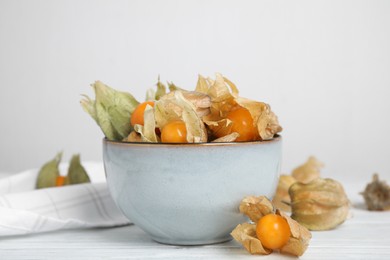 Photo of Ripe physalis fruits with dry husk on white wooden table