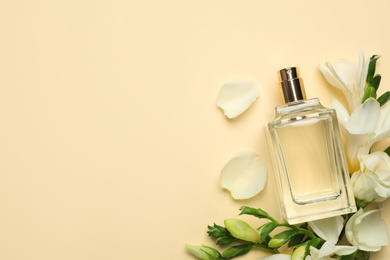 Photo of Flat lay composition with bottle of perfume and freesia flowers on yellow background, space for text