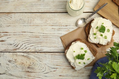 Bread with cream cheese, green onion and parsley on white wooden table, flat lay. Space for text