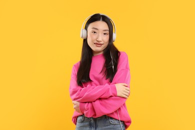Photo of Portrait of beautiful woman in headphones on orange background