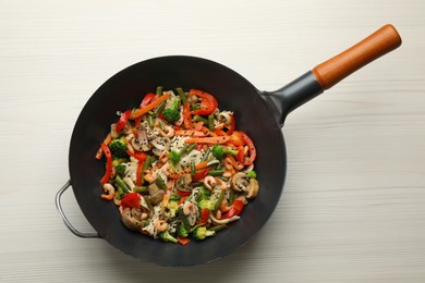Stir fried noodles with mushrooms, shrimps and vegetables in wok on white wooden table, top view