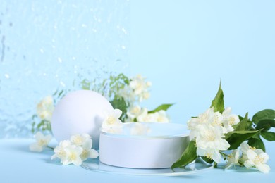 Photo of Presentation of product. White podium and beautiful jasmine flowers on light blue background