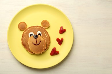 Photo of Creative serving for kids. Plate with strawberries, cute bear made of pancakes on light wooden table, top view Space for text