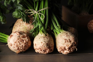 Photo of Fresh raw celery roots on wooden table, closeup