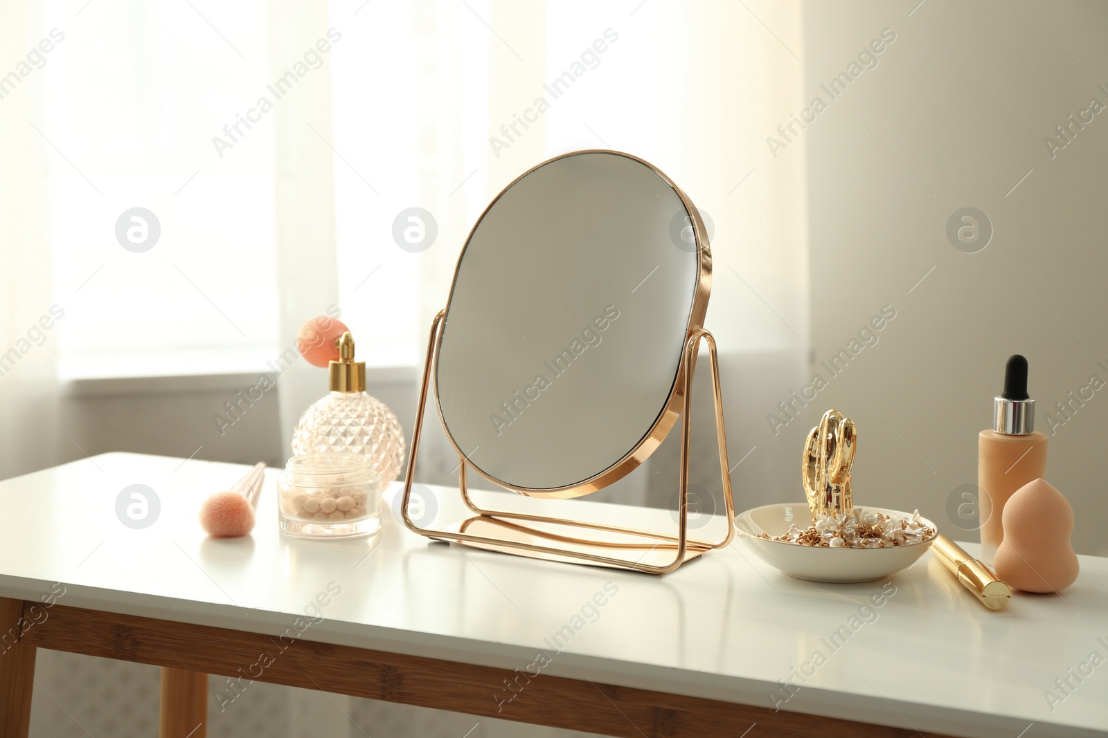 Photo of Mirror and makeup products on white table indoors