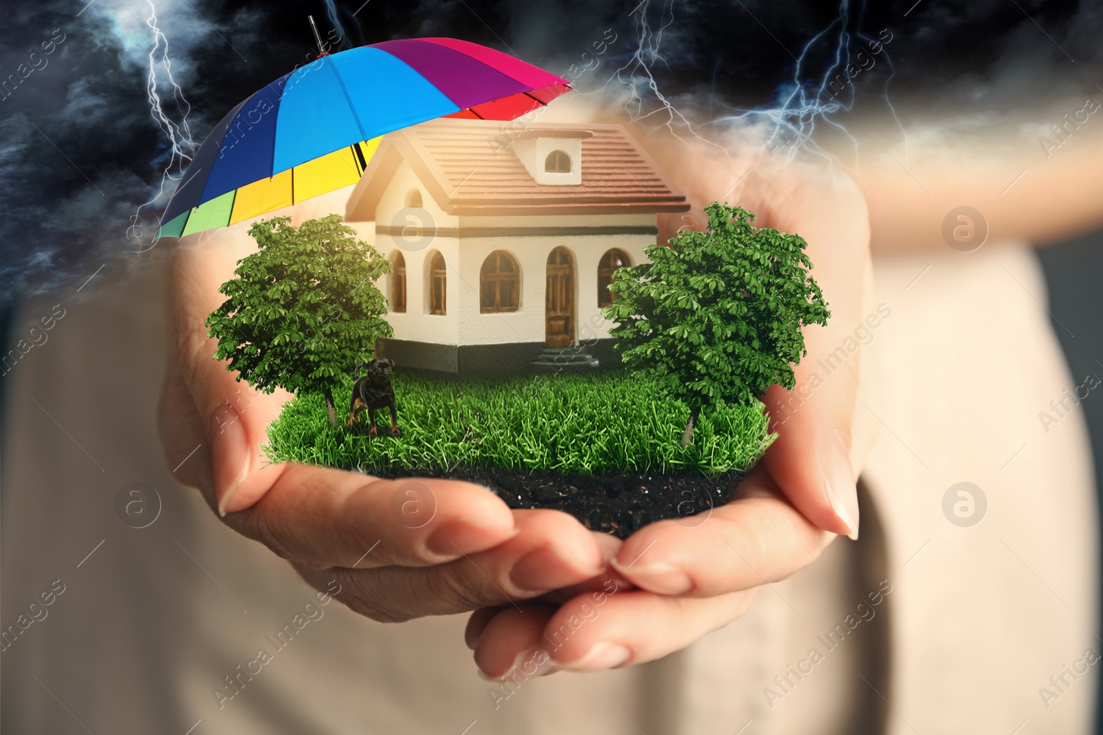 Image of Insurance concept - umbrella demonstrating protection. Woman holding house model with green lawn, closeup