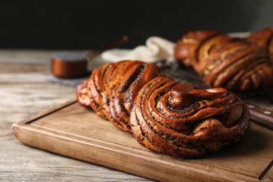 Photo of Tasty sweet buns with poppy seeds on wooden table