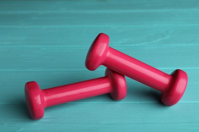Photo of Pink vinyl dumbbells on turquoise wooden table