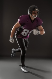 Photo of American football player wearing uniform on dark background