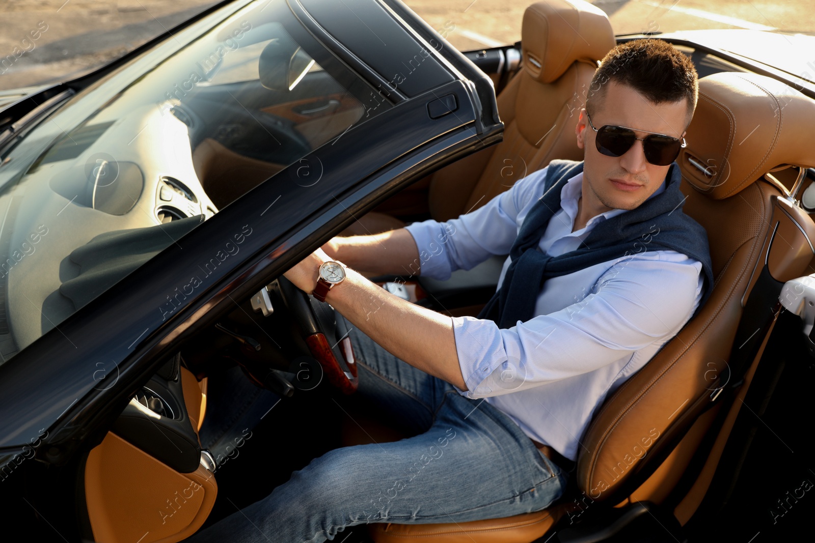 Photo of Handsome young man in luxury convertible car outdoors