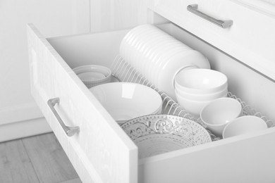 Photo of Open drawer with different plates and bowls in kitchen