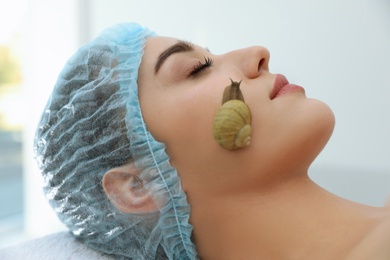 Young woman receiving snail facial massage in spa salon, closeup