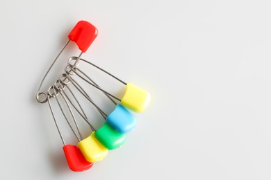 Photo of Colorful safety pins on white background, flat lay. Space for text